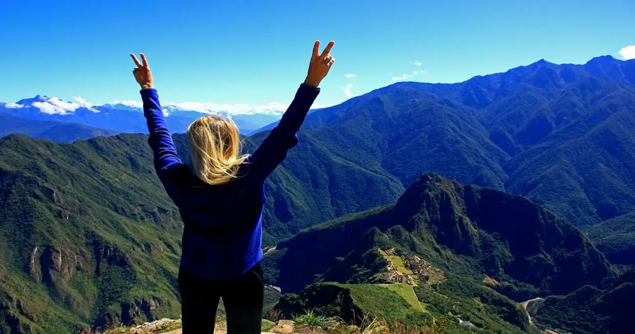 Tourist standing on Machu Picchu Mountain, enjoying panoramic views of the ancient Inca citadel and the surrounding Andes | Andean Travel Experience