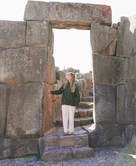 Woman standing at the Sun Gate of Sacsayhuamán, Cusco | Andean Travel Experience