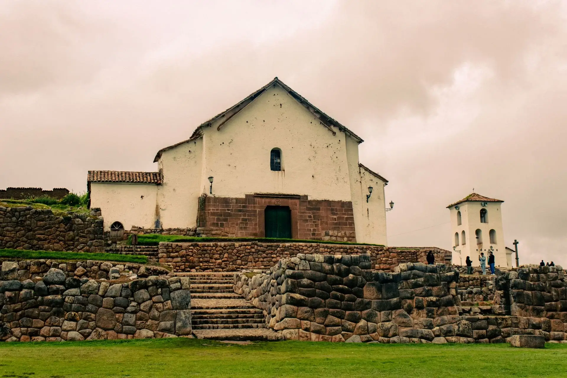 House in the town of Chincheros rocks and green land on a cloudy day | Andean Travel Experience