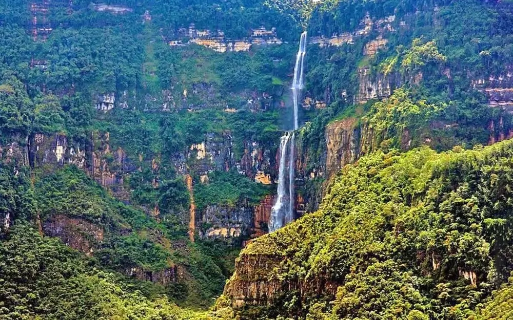 Chinata Waterfall in Amazonas, Peru, cascading down lush green cliffs surrounded by tropical vegetation and misty mountain air. | Andean Travel Experience