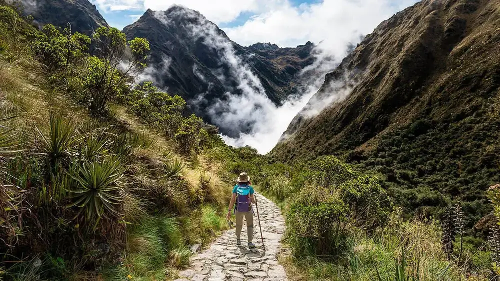 Ancient stone section of the Qhapaq Ñan crossing the Andes Mountains under a dramatic sky | Andean Travel Experience