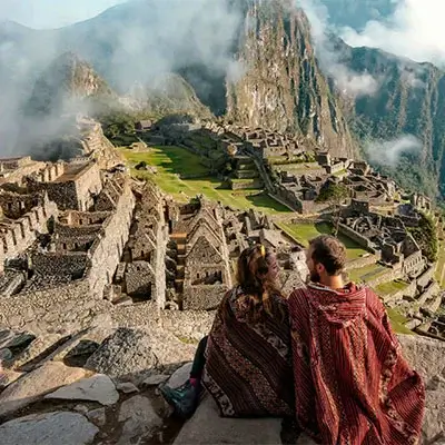 Couple enjoying the breathtaking views of Machu Picchu, Peru, with the ancient Inca citadel and lush mountains in the background | Andean Travel Experience