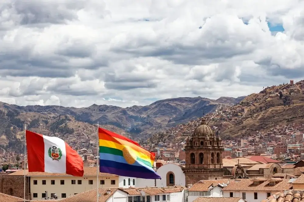 Rainbow flag of Cusco waving against a clear blue sky, representing the cultural diversity and heritage of the Andean city in Peru | Andean Travel Experience