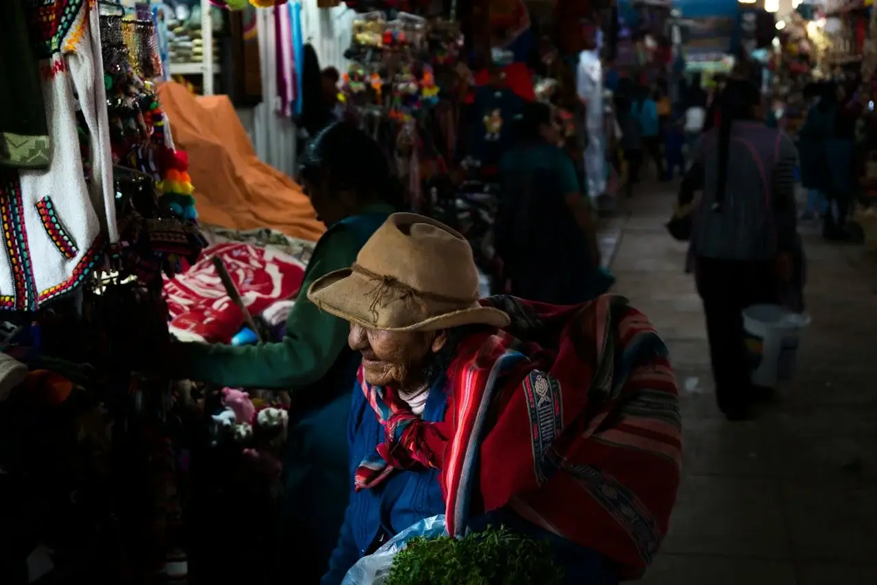 Colorful local market in Cusco, Peru, with vendors selling fresh produce, traditional textiles, and Andean crafts in a lively atmosphere. | Andean Travel Experience