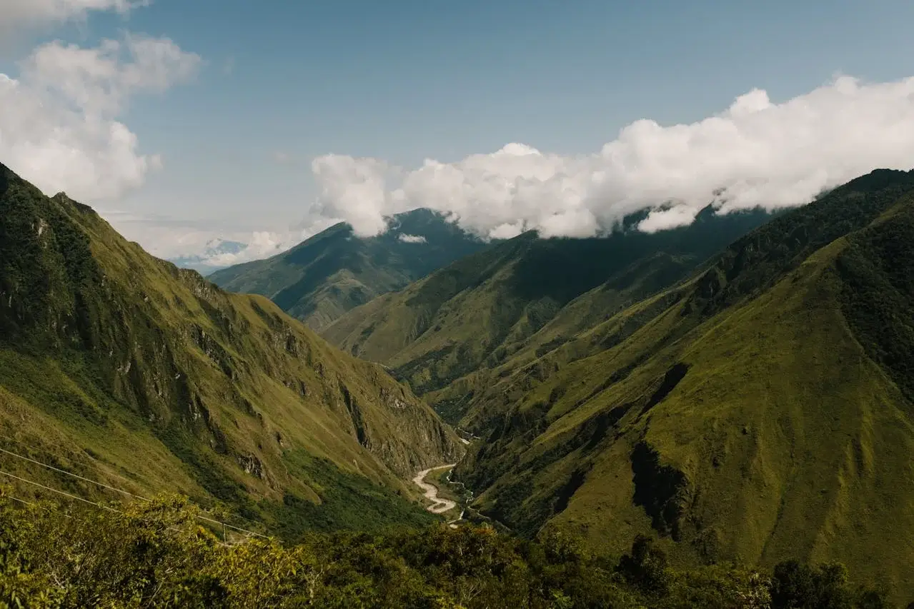 Lush green Andean mountains with a winding river flowing through the valley in Peru, a scenic destination for sustainable travel and adventure. | Andean Travel Experience