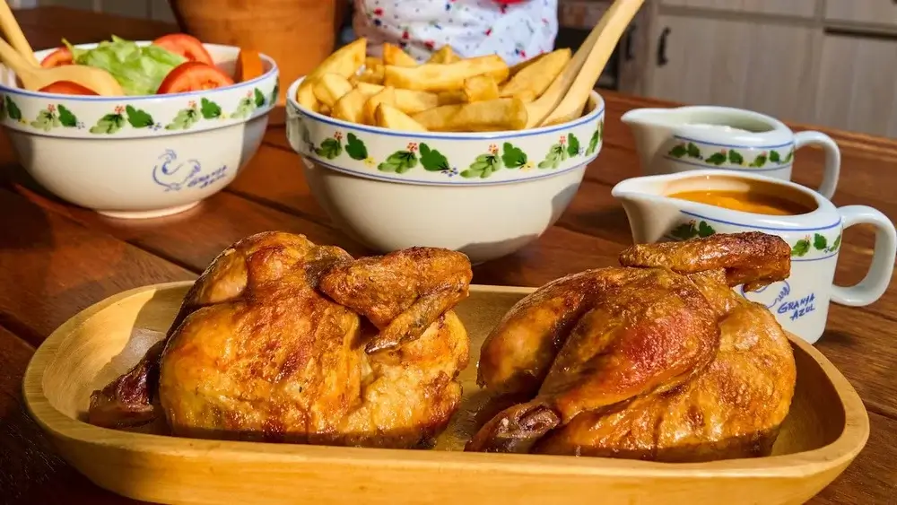 Pollo a la Brasa from La Granja Azul, served with crispy fries, salad, and signature sauces in a rustic Peruvian setting. | Andean Travel Experience