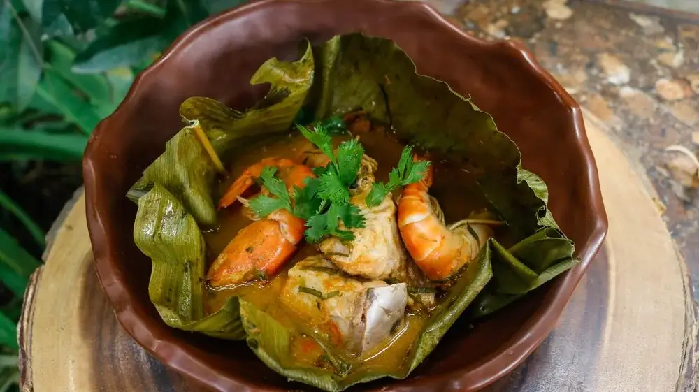 Classic Peruvian Amazon dish patarasca, consisting of marinated river fish wrapped in bijao leaves and grilled, served with rice and fried plantains. | Andean Travel Experience