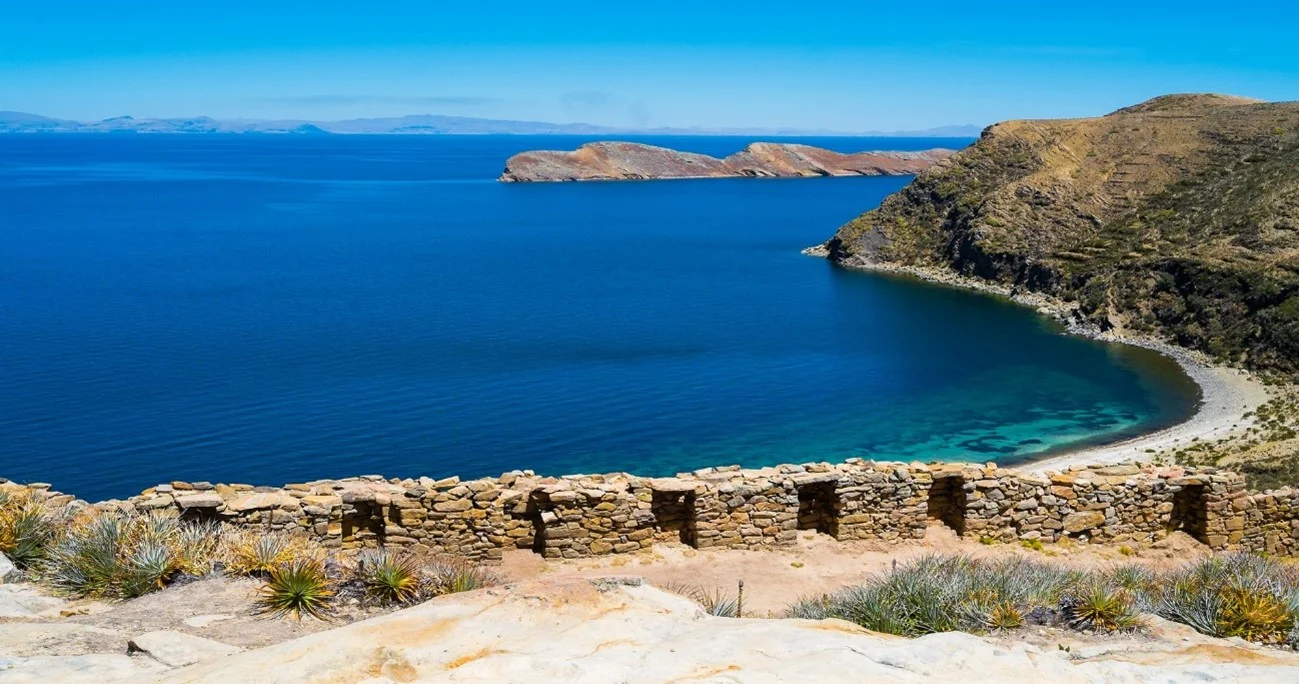 Crystal-clear waters of Lake Titicaca reflecting the surrounding mountains | Andean Travel Experience