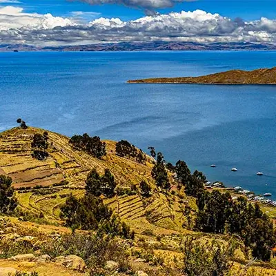 Scenic view of Lake Titicaca, with clear blue waters and surrounding Andean landscape, spanning Peru | Andean Travel Experience