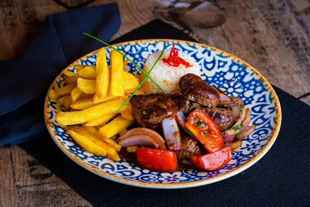 Lomo saltado – sautéed beef with onions, tomatoes, soy sauce, served with rice and fries, traditional Peruvian dish | Andean Travel Experience