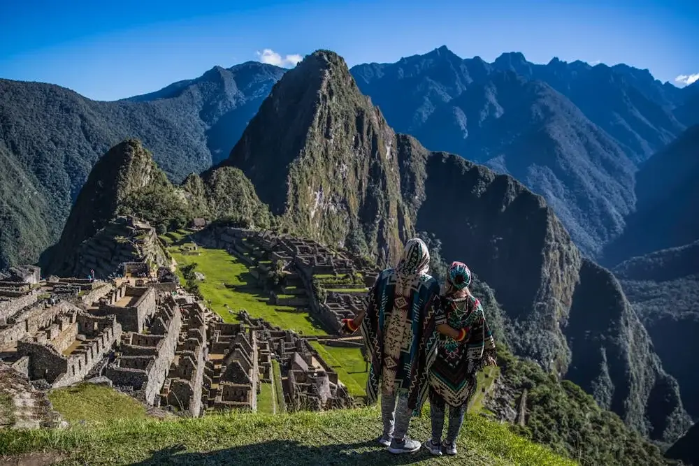 Couple standing together overlooking the ancient terraces of Machu Picchu, surrounded by misty mountains and sunrise light. | Andean Travel Experience