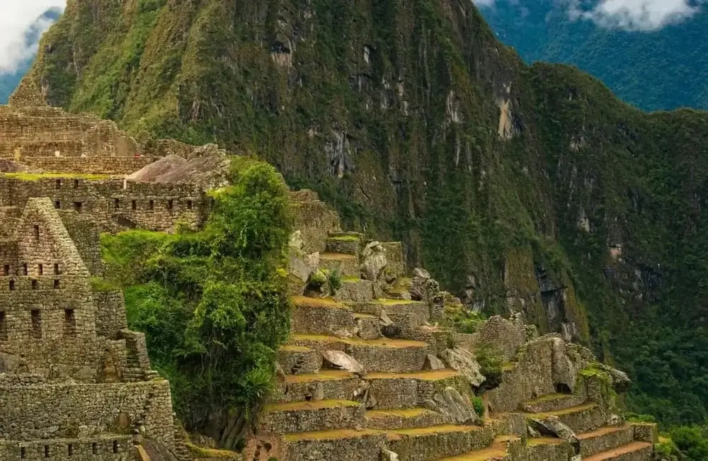 Ancient Inca stone terraces of Machu Picchu surrounded by lush green Andes mountains | Andean Travel Experience