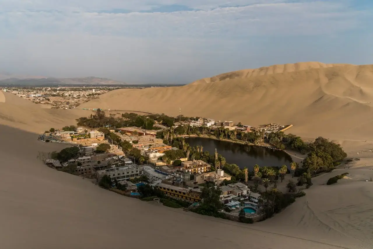 Huacachina Oasis surrounded by golden desert dunes in Ica, Peru | Andean Travel Experience