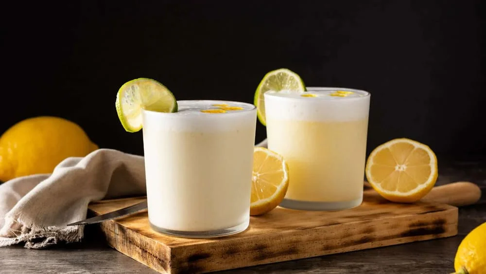 Classic Pisco Sour cocktail in a glass, garnished with frothy egg white foam and a few drops of Angostura bitters, symbolizing Peru’s national drink | Andean Travel Experience