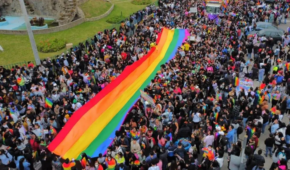 Crowds celebrating Pride Month in Lima march through the streets carrying a large rainbow LGBT flag, surrounded by colorful banners and joyful participants waving in support of diversity and inclusion. | Andean Travel Experience Crowds celebrating Pride Month in Lima march through the streets carrying a large rainbow LGBT flag, surrounded by colorful banners and joyful participants waving in support of diversity and inclusion. | Andean Travel Experience
