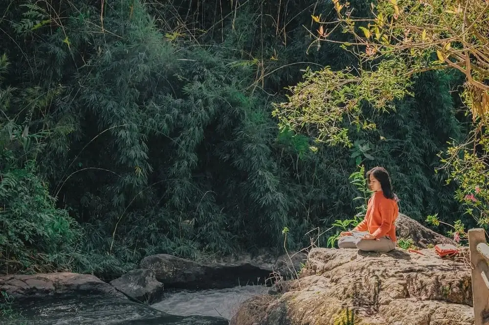 Traveler relaxing in the Sacred Valley of Peru, surrounded by peaceful mountain views, lush greenery, and the calming flow of the Urubamba River. | Andean Travel Experience