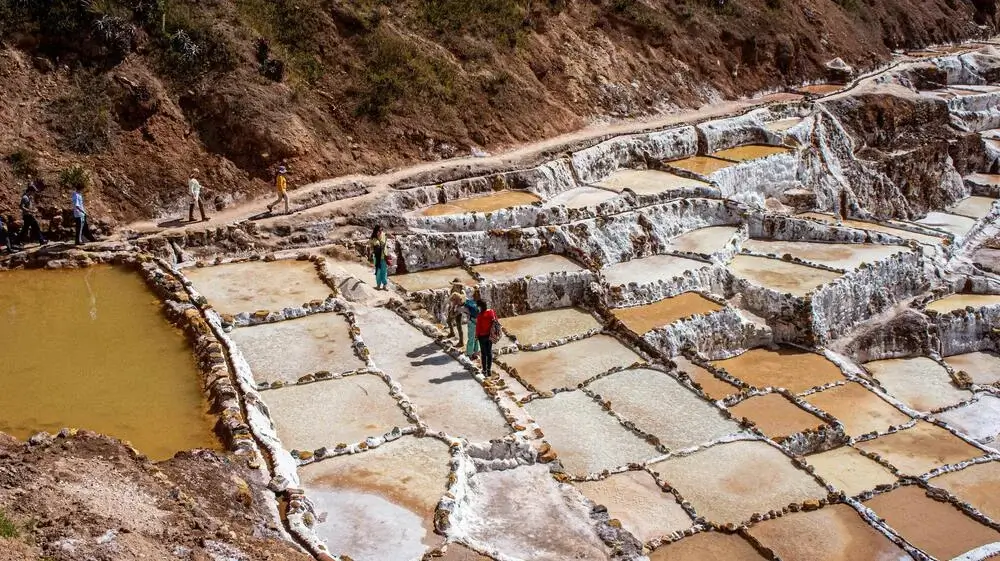 Natural salt crystals forming in evaporation pools at the Maras Salt Mines, a centuries-old salt harvesting site in Peru. | Andean Travel Experience