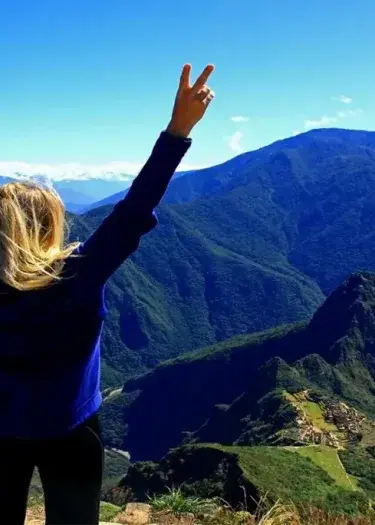 Tourist standing on Machu Picchu Mountain, Peru, with panoramic views of the ancient Inca ruins and surrounding Andes | Andean Travel Experience