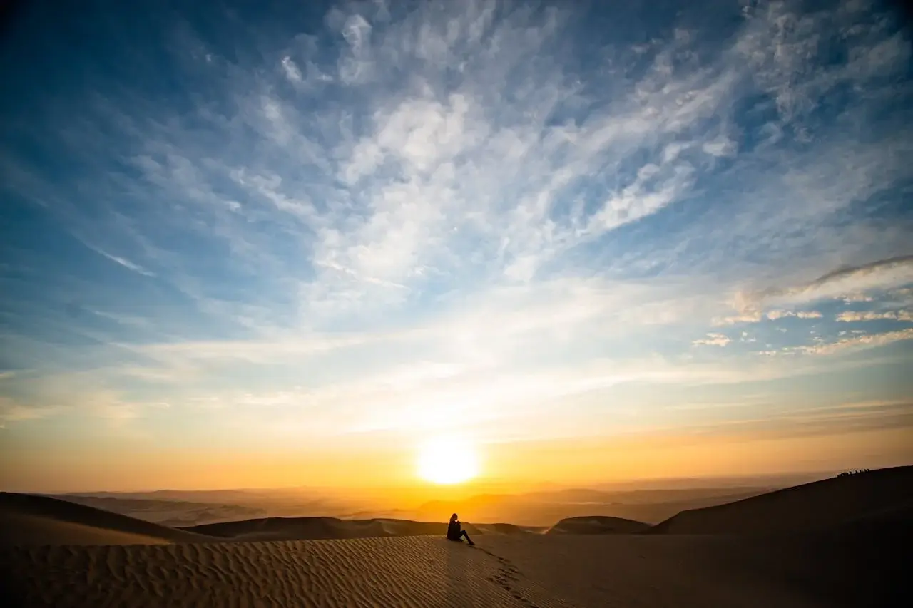 Golden sunset over the sand dunes of Ica, Peru, with soft light illuminating the desert landscape. | Andean Travel Experience Golden sunset over the sand dunes of Ica, Peru, with soft light illuminating the desert landscape. | Andean Travel Experience