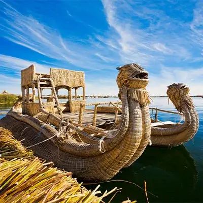 Uros floating islands with a traditional totora reed boat on Lake Titicaca, Peru | Andean Travel Experience